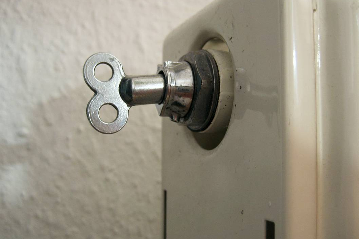 Chave de purga inserida na válvula de purga de um radiador doméstico