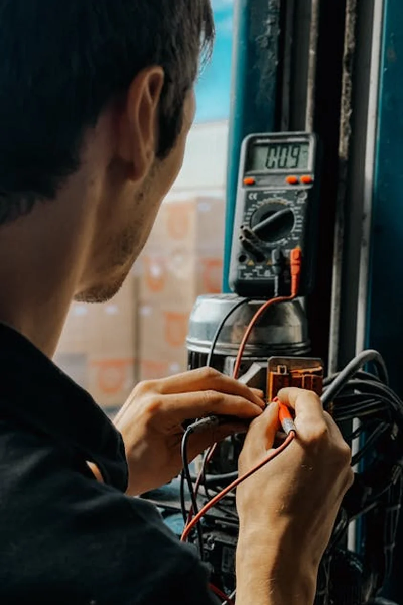 Eletricista a usar verificador de tensão (multímetro) para confirmar ausência de corrente nos fios