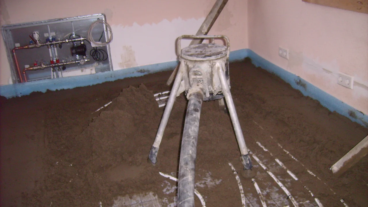 Instalação de betonilha flutuante sobre subcamada resiliente com fita perimetral azul nas paredes e tubagem de piso radiante, técnica utilizada para isolamento acústico de pavimentos