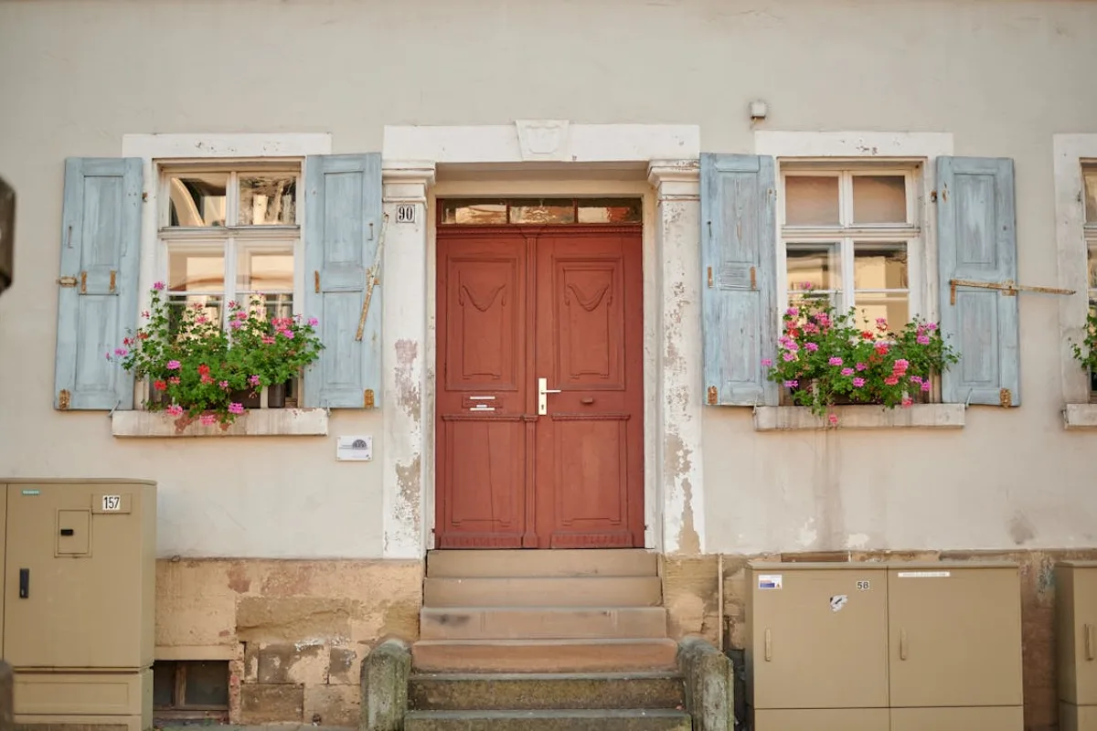 Entrada exterior de uma casa bem cuidada com porta pintada e jardim arrumado — primeira impressão positiva para compradores