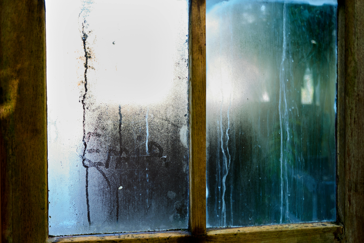 Condensação no vidro de janela de madeira com gotas de água visíveis no interior