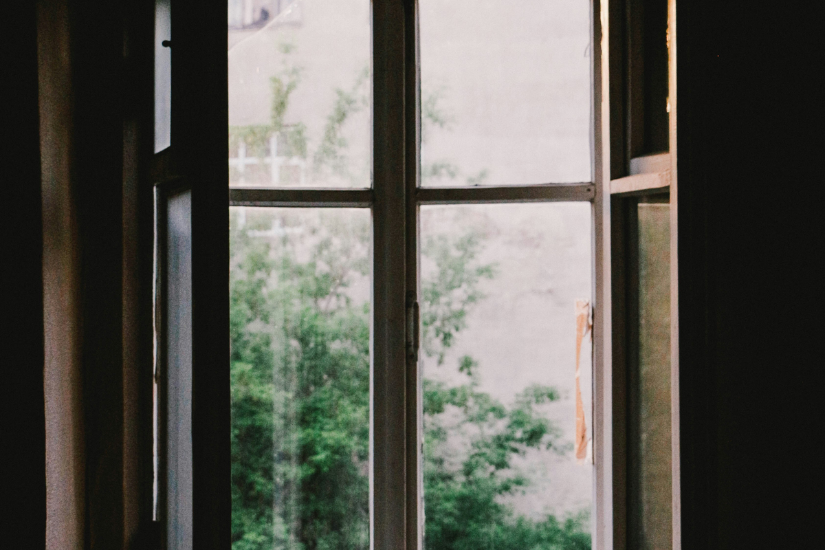 Janela de batente aberta com plantas junto ao parapeito para ventilação natural
