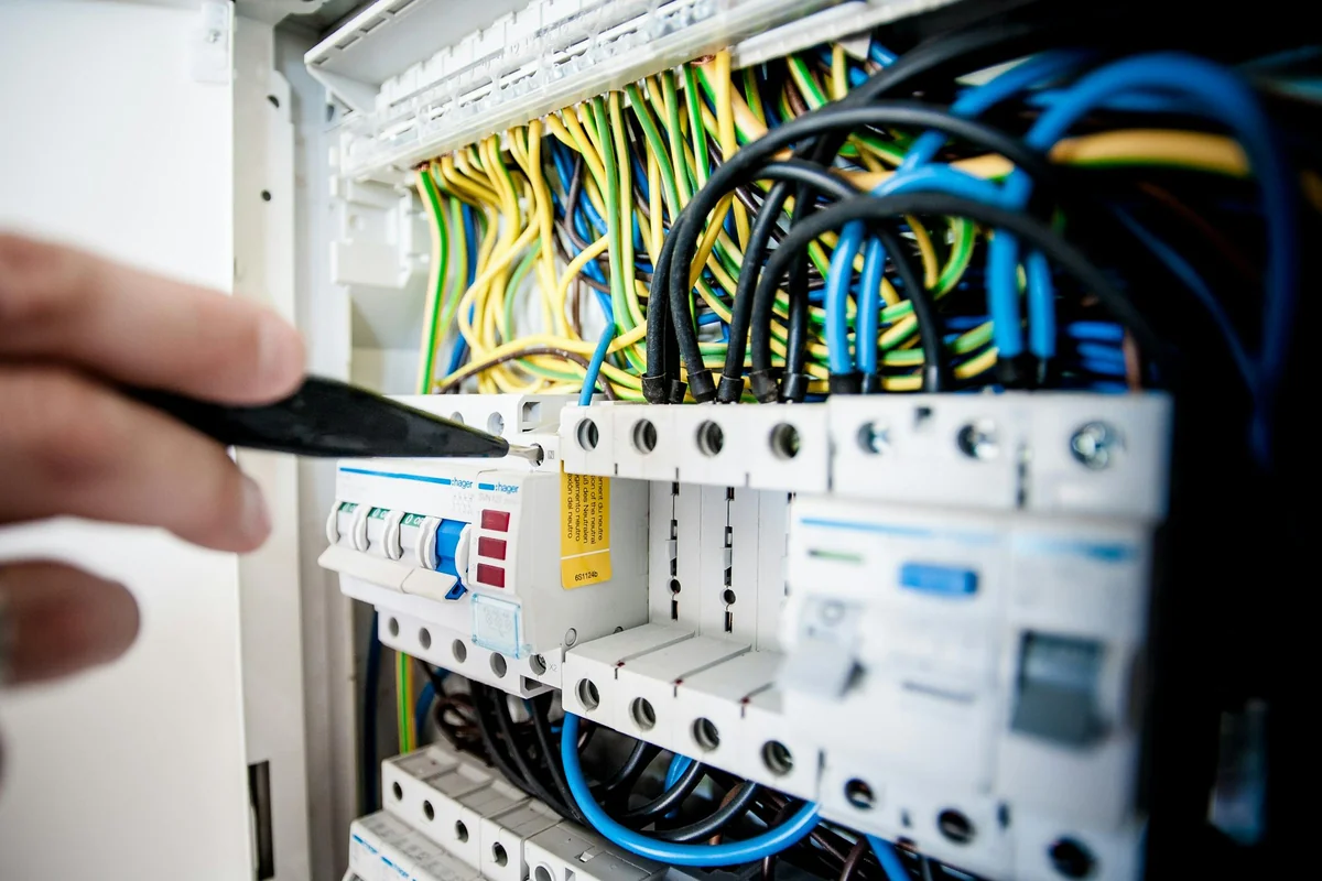 Mão a verificar disjuntores num quadro elétrico europeu — passo 1 para resolver tomada sem corrente