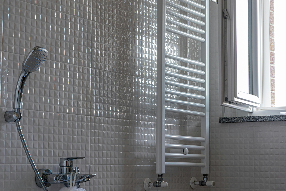 Casa de banho com banheira branca, toalheiro aquecido e janela — contexto europeu de substituição de silicone