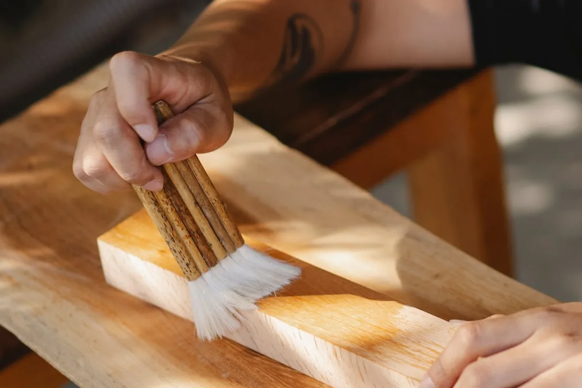 Artesão a aplicar produto fungicida e preservante em madeira exterior com pincel